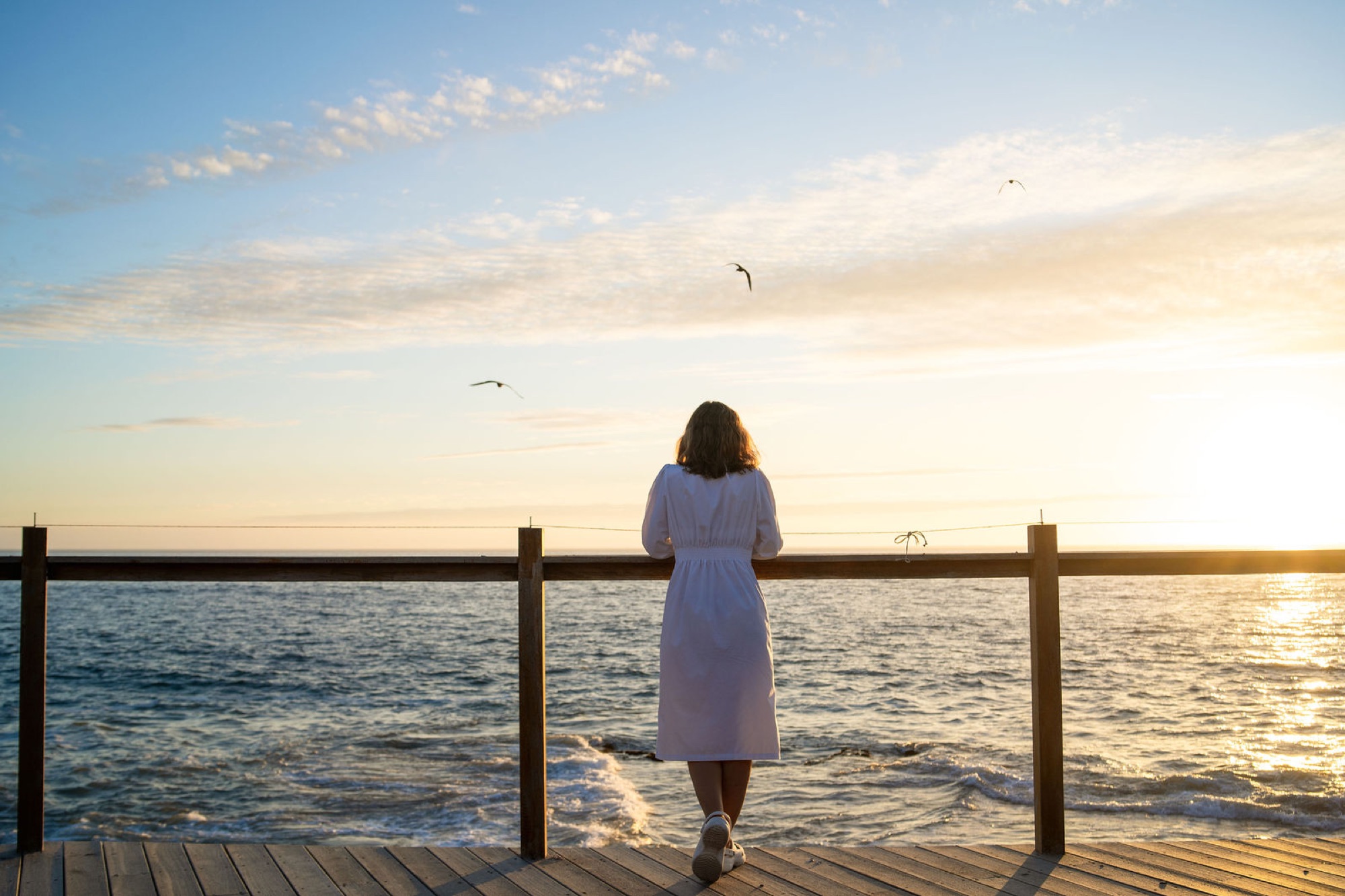 A patient on the Santa Maria deck at sunrise, looking at the Pacific